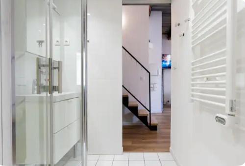 un couloir blanc avec un escalier et une porte en verre dans l'établissement Maison Pépouze, à Marseille