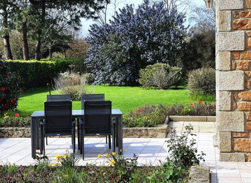 - une table avec quatre chaises noires sur la terrasse dans l'établissement Steredennvor, à Pleubian