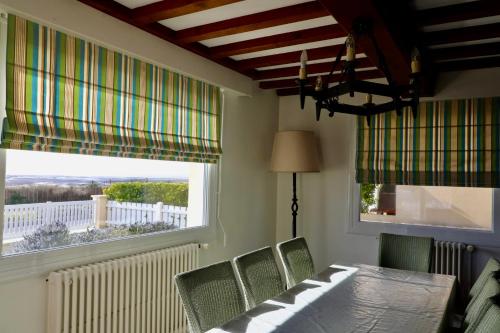 Un comedor con mesa y sillas y una ventana. en Villa facing sea and beach 7 pers 1 baby, en Barneville-Carteret