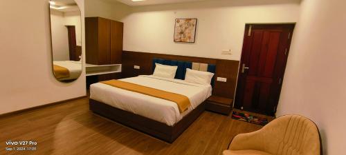 a bedroom with a bed and a chair and a mirror at Raja Hill Resorts in Kodaikānāl