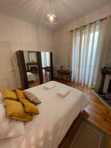 - une chambre avec un grand lit blanc et des oreillers jaunes dans l'établissement LE SAINT JULIEN 3étoiles - Hypercentre - Proche Thermes - Balcon, à Vichy