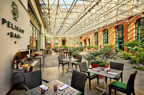 a restaurant with tables and chairs in a building at Sheraton Hannover Pelikan Hotel in Hannover