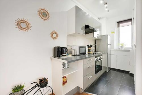 Il comprend une cuisine avec des placards blancs et du carrelage noir au sol. dans l'établissement Charming apartment -4P- Arc de Triomphe, à Paris
