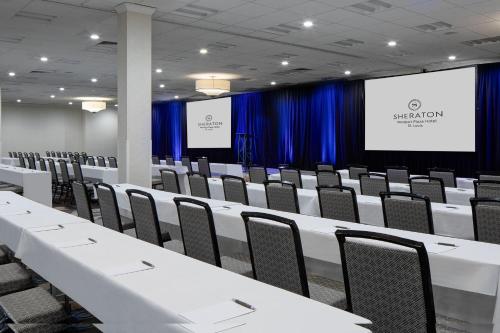 a conference room with white tables and chairs and a screen at Sheraton Westport Plaza in Maryland Heights