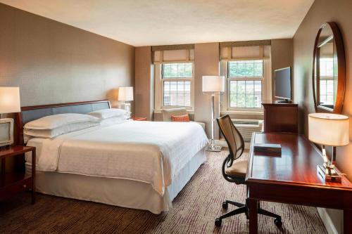 a hotel room with a large bed and a desk at Sheraton Commander Hotel in Cambridge