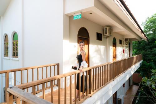 a woman standing on the balcony of a house at Baan Imm Sook Resort in Chao Lao Beach