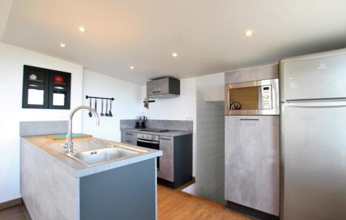 une cuisine avec un évier et un réfrigérateur dans l'établissement Le Chalet, les pieds dans l'eau, à Asnelles