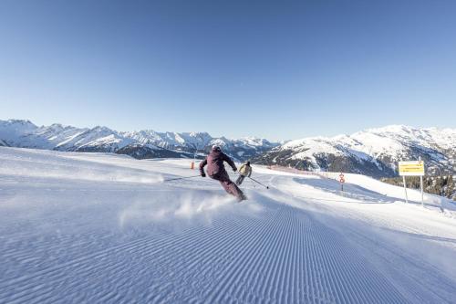 two people are skiing down a snow covered slope at Landhaus Sabine in Zellberg