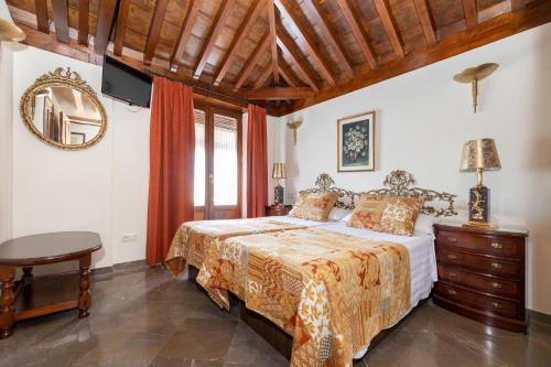 a bedroom with a bed and a table and a mirror at Aljibe Rodrigo del Campo 2B in Granada