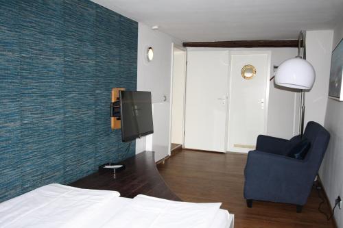 a bedroom with a bed and a chair and a tv at Elements Hotel in Regensburg