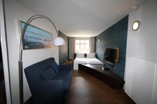 a living room with a blue couch and a tv at Elements Hotel in Regensburg