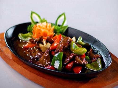a bowl of food with meat and vegetables on a table at Yusro Hotel Restaurant & Convention in Jombang