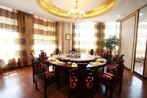 a dining room with a table and chairs and a chandelier at Dalian Bohai Pearl Hotel in Dalian