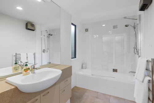 a white bathroom with a sink and a bath tub at *** LAKE VILLA 458 *** in Hanmer Springs