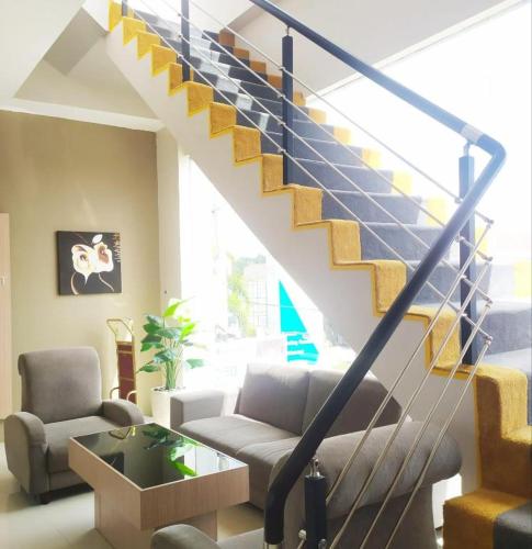 a living room with a staircase with a couch and a table at Zenith Hotel in Kendari