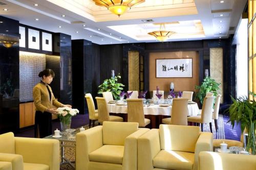 a woman standing in a dining room with a table at International Conference Hotel Nanjing in Nanjing