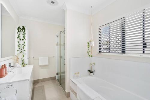 een witte badkamer met een bad en een wastafel bij Solace on Castleton - Modern, Spacious, Private in Smithfield