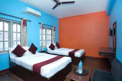 two beds in a room with blue and orange walls at OYO 381 Hotel Pashupati Plaza in Kathmandu