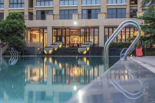 a swimming pool with a slide in front of a building at Da Peng Zhongzhou Hotel in Haikou