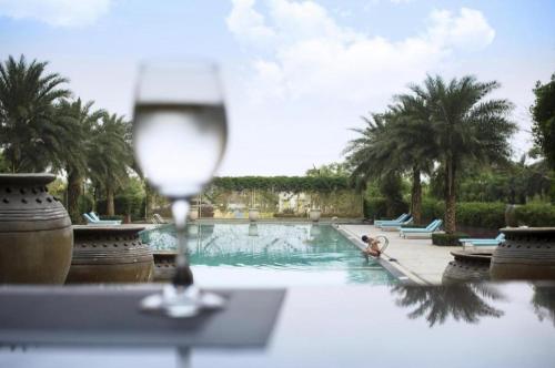 a glass of wine sitting on a table next to a pool at Da Peng Zhongzhou Hotel in Haikou