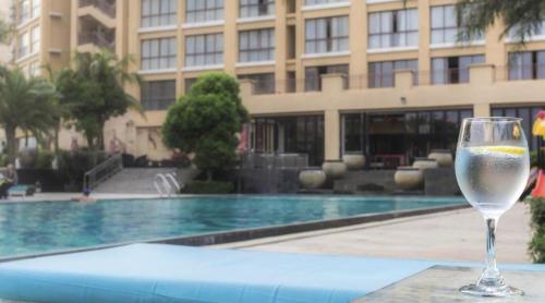 a glass of wine sitting on a table next to a pool at Da Peng Zhongzhou Hotel in Haikou