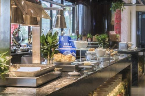 a buffet line with plates of food in a restaurant at Da Peng Zhongzhou Hotel in Haikou