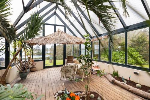 a conservatory with a table and chairs in a room with windows at Luxury House on Seafront in Curryglass