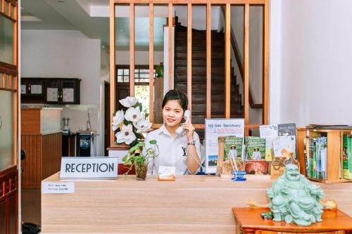 a woman talking on a phone behind a counter at Kim's Villa Hoi An in Hoi An