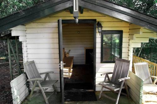 a small shed with two chairs and a door at Luxury House on Seafront in Curryglass