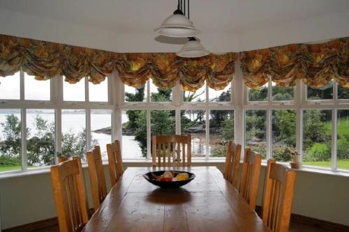 a dining room table with chairs and a bowl of fruit on it at Luxury House on Seafront in Curryglass