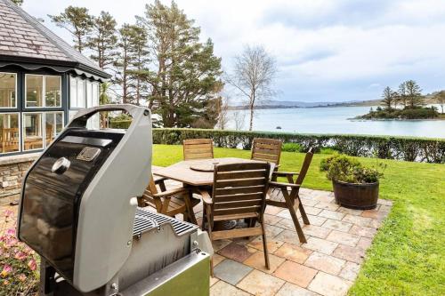 a bbq on a patio with a table and chairs at Luxury House on Seafront in Curryglass
