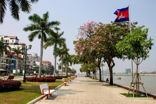 a flag flying over a sidewalk next to a river at Asia Hotel in Phnom Penh
