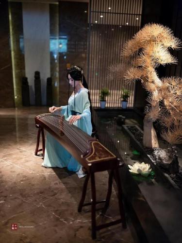 a woman sitting on a bench in a building at Yuan Culture Hotel Shenzhen World Shajing in Shenzhen