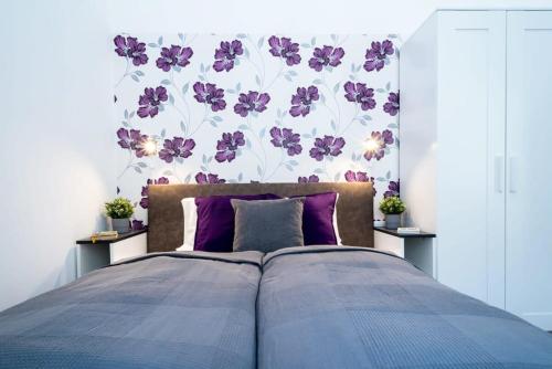 a bedroom with a bed with purple pillows and a floral wall at Modern Intimate Studio in the center in Budapest