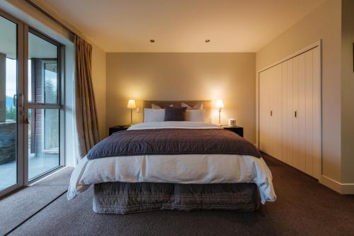 a bedroom with a large bed and a large window at Amuri Estate Luxury Lodge in Hanmer Springs