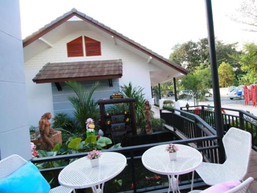 a balcony with two tables and chairs and a house at Phakawan Hotel in Maha Sarakham