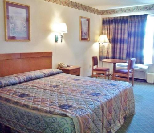a hotel room with a bed and a table and chairs at America's Best Inn - Brinkley in Brinkley