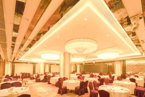 a banquet hall with white tables and chairs and a chandelier at King Century Hotel in Zhongshan