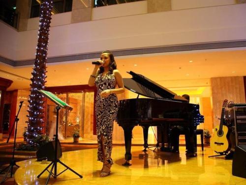a woman is standing in front of a piano at King Century Hotel in Zhongshan