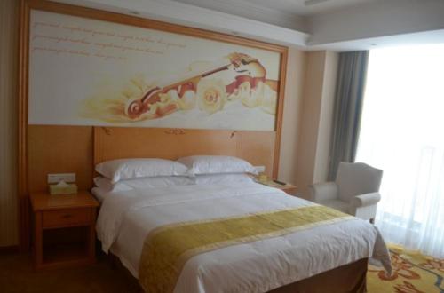 a bedroom with a bed and a large painting on the wall at Vienna Classic Hotel Qingdao Huangdao in Huangdao