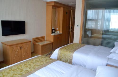 a hotel room with two beds and a television at Vienna Classic Hotel Qingdao Huangdao in Huangdao