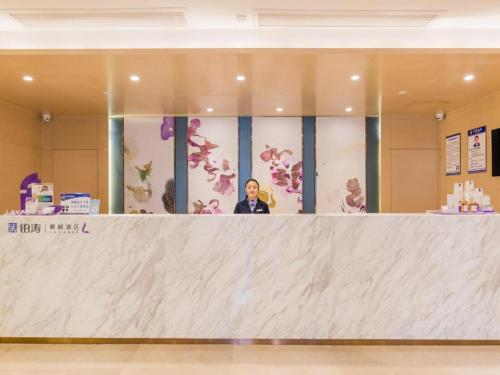 a man standing behind a counter in a lobby at Lavande Hotels·Yichang Wanda Plaza in Yichang