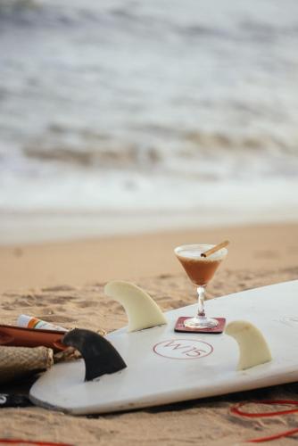 a white surfboard with a drink on the beach at W15 Weligama in Weligama