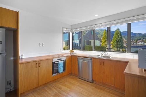 a kitchen with wooden cabinets and a large window at *** LAKE VILLA 466 *** in Hanmer Springs