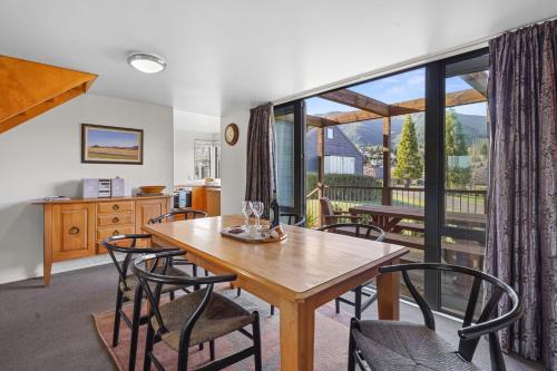 a dining room with a table and chairs and a large window at *** LAKE VILLA 466 *** in Hanmer Springs