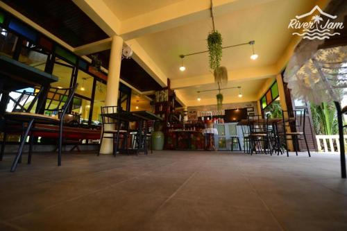 a restaurant with tables and chairs in a building at River Jam Amphawa in Amphawa