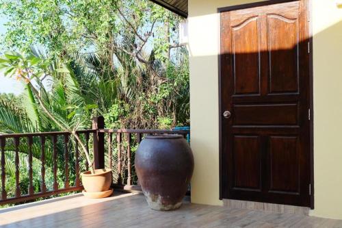 a large vase sitting on a porch next to a door at River Jam Amphawa in Amphawa