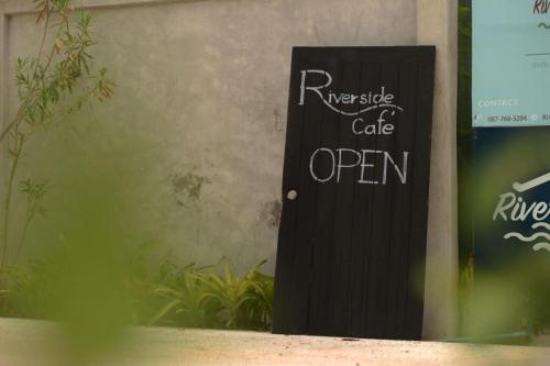 a sign on a door that reads refugee cafe open at River Jam Amphawa in Amphawa