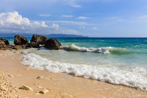 a beach with rocks and the ocean with waves at Aloe de Diniwid in Boracay