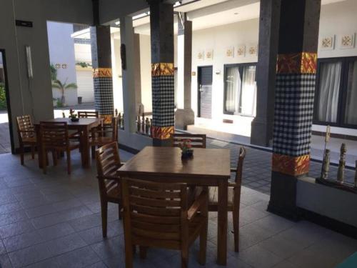 a restaurant with wooden tables and chairs and windows at Asoka City Bali Hotel in Legian